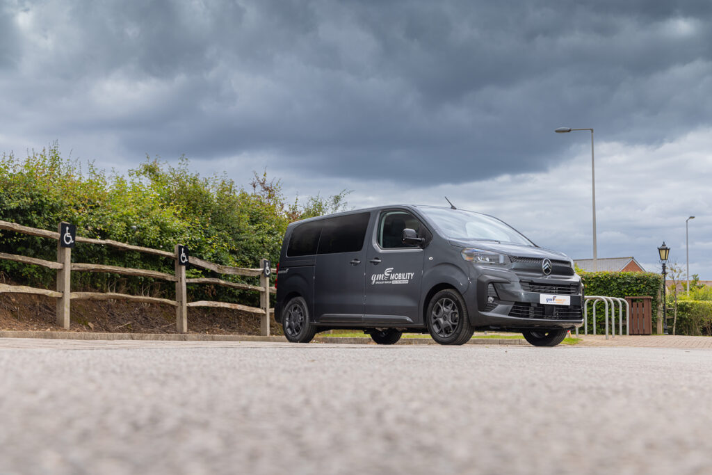 A grey Citroen Spacetourer WAV, Quantum model converted by GM Coachwork, parked in front of a hedge angled side-on.